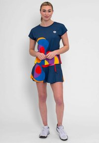 Conjunto de camiseta y pantalones cortos deportivos en color azul marino con grandes patrones geométricos multicolores. La tela es suave, con un corte relajado y mangas cortas.