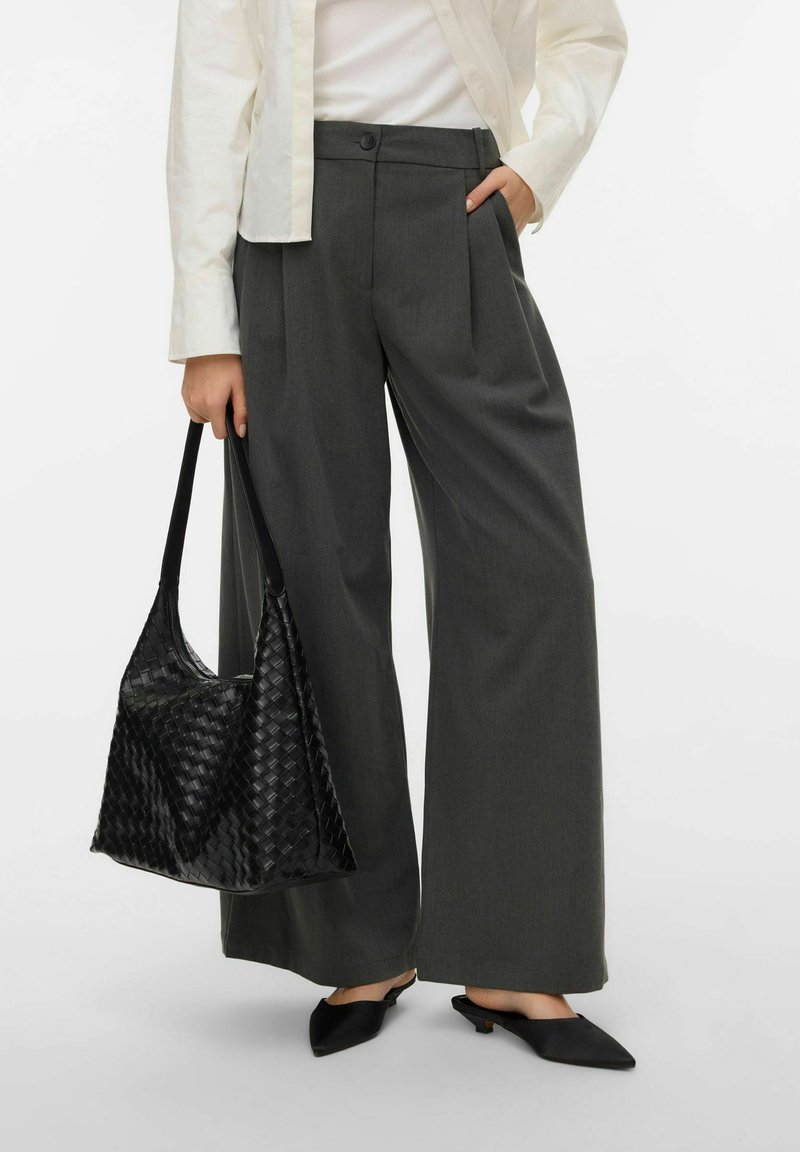 Szare spodnie o szerokich nogawkach z przednimi plisami, zestawione z fakturowaną czarną plecioną torebką i czarnymi szpiczastymi mule. Pod spodem biała koszula.