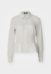 Lys beige skjorte med lange ermer, krage, knappestolpe, samlet liv og peplum-nederdel. Laget av et teksturert stoff.