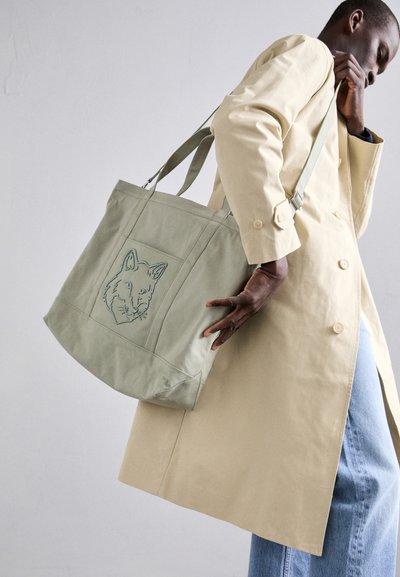 Bolsa de lona verde con diseño de zorro bordado, con asas resistentes, forma rectangular y un acabado suave y texturizado.