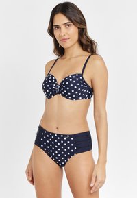 Navyblaues Bikini-Set mit weißen quadratischen Mustern, bestehend aus einem gepolsterten Unterbrusttop und einem hüfthohen Bottom mit Raffung an den Seiten.