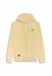 Haut à capuche beige avec poche frontale, cordons de serrage et petit logo noir "Redskins" sur la poitrine et dans le coin inférieur gauche de la poche.