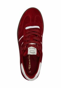 Sneaker rossa in suede con accenti bianchi, punta arrotondata, tomaia testurizzata e lacci piatti. Logo e etichetta della taglia visibili sulla fodera interna.