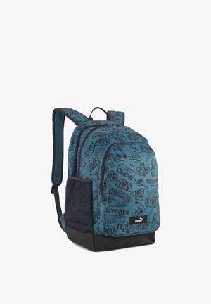 Sac à dos Teal Puma avec imprimé noir style graffiti, multiples compartiments zippés, poche latérale en mesh et bretelles rembourrées et ajustables.