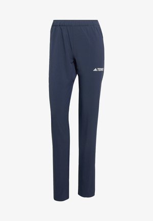 Marineblå treningsbukser laget av lett materiale, med elastisk midjebånd og en hvit "TERREX"-logo på siden.