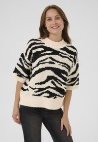 Knitted, short-sleeve sweater in cream with black zebra stripes; soft texture and crew neckline with ribbed hem and cuffs.