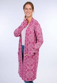 Long, open-front cardigan in bright pink with white floral patterns, two front pockets, and long sleeves, made from lightweight fabric.