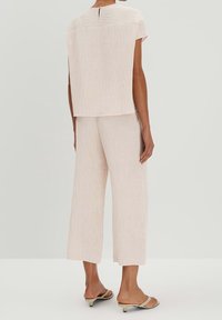 Ljusrosa, texturerat co-ord set med en fyrkantig topp med korta ärmar och korta byxor, kombinerat med ljusa slip-on sandaler.