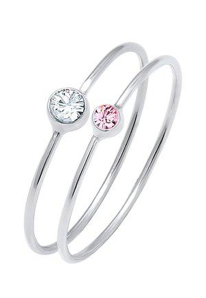 Deux bagues en argent avec des anneaux fins, chacune sertie d'une seule pierre ronde — une claire et une rose clair — sur fond blanc.