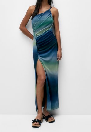 Robe de fête froncée en dégradé bleu et vert, avec une fente latérale, des bretelles fines et une texture de tissu lisse et brillante.