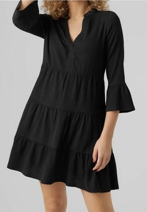 Black dress with a textured, pleated fabric. It features a deep V-neck, three-quarter bell sleeves, and a tiered skirt design.