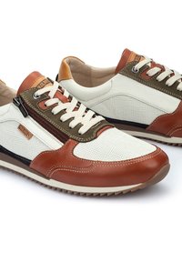 Sneakers con una toma in rete bianca, dettagli in pelle marrone e particolari in verde oliva. Presentano lacci e una cerniera laterale per facilità d'uso.