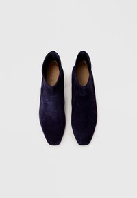 Navy blue suede ankle boots with a pointed toe, minimal stitching, and no visible hardware. Smooth texture and sleek silhouette.
