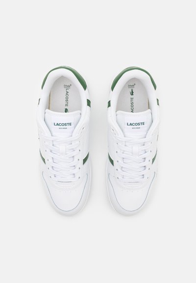 Бели маратонки Lacoste със зелени акценти на петата, връзки и лого, показани отгоре на бял фон.