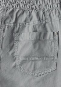 Grå shorts med elastisk midja och en bakficka som stängs med en metallknapp. Slät, lättviktig tyg med en subtil lyster.