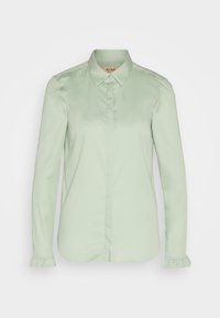 Blouse vert clair à manches longues avec col pointu, boutons avant cachés et poignets volantés aux manches.