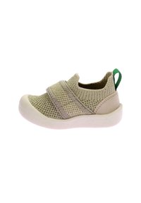 Scarpa slip-on in mesh beige con fasce elastiche, un'etichetta a contrasto verde e una suola bianca con un motivo testurizzato.