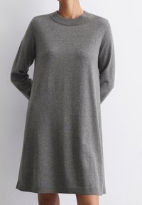 Abito in maglia grigio con maniche lunghe, scollatura rotonda e vestibilità rilassata. Presenta un orlo che termina sopra il ginocchio e una consistenza sottile.
