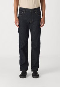 Jeans de mezclilla azules oscuros con un corte recto. Cuentan con cinco bolsillos, costuras visibles y un cierre de botón en la cintura.