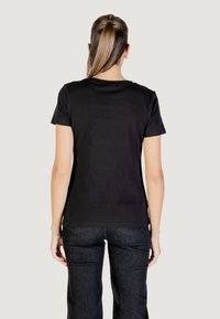 T-shirt in cotone nero con maniche corte e scollatura rotonda, abbinata a jeans in denim scuro. Tessuto liscio con una silhouette aderente.
