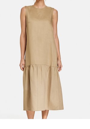 Sleeveless beige midi dress with a gathered seam above the hem, worn by a standing person against a plain background.