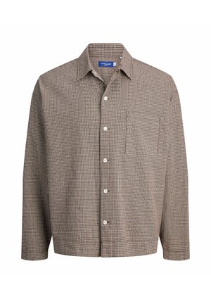 Koszula w brązową kratę na czarnej koszulce z grafiką, zestawiona z szerokimi ciemnoniebieskimi dżinsami oraz beżowymi trampkami z białymi akcentami.