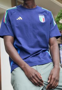 Granatowa bawełniana koszulka z logo Włoch i czterema gwiazdkami, z zielonymi i czerwonymi paskami na ramionach oraz niebieskimi panelami bocznymi.