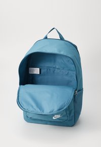 Μπλε σακίδιο νάιλον με ευρύχωρο κύριο διαμέρισμα, τσέπη με φερμουάρ μπροστά και λαβή για μεταφορά από πάνω. Διαθέτει ένα μικρό λογότυπο μπροστά.