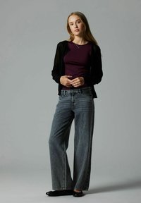 Black sheer cardigan over a dark purple top, paired with loose gray denim jeans. Outfit completed with black flat shoes. Simple and modern design.