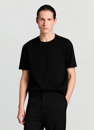 Schwarzes T-Shirt mit kurzen Ärmeln aus strukturiertem Stoff und Rundhalsausschnitt. Kombiniert mit maßgeschneiderten schwarzen Hosen mit elegantem, minimalistischem Design.