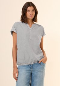 Striped blouse in black and white, short sleeves, V-neck, elastic hem, paired with light blue wide-leg jeans. Smooth texture, casual design.