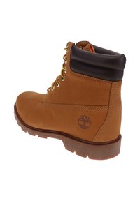 Bottine de travail en cuir tan avec un col rembourré noir, des lacets jaune-rouge, une semelle robuste et un logo d'arbre en relief sur le côté.