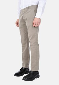 Pantaloni in cotone beige con design a gamba dritta, dotati di chiusura con bottone anteriore e tasche, abbinati a scarpe eleganti in pelle nera.