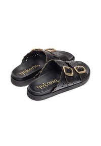 Sandalias de slide negras con parte superior de cuero perforado, dos hebillas en tono dorado, suela negra acolchada y logo grabado en la plantilla.