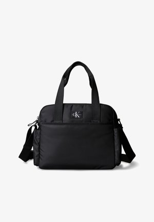 Czarna torebka Calvin Klein na ramię i do ręki z przednią kieszenią, dwoma uchwytami i regulowanym paskiem na białym tle.
