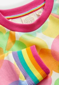 Multikleurige sweatshirt met een roze geribbelde kraag, gedurfde geometrische patronen in oranje, groen en geel, met gestreepte accenten op de mouwen.