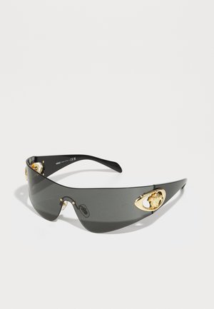 Lunettes de soleil noires avec un design courbé et élégant. Présentent des accents de lion dorés sur les côtés et une monture noire brillante.