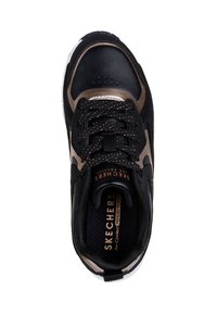 Svart idrottssko med guldaccenter, texturerad ovandel och snörning. Har en märkesinläggssula och gummisula. Ventilationshål nära tårna.