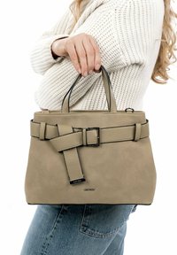Beige Lederhandtasche mit einer strukturierten Oberfläche, oberen Griffen und einem Gurt-Detail. Verfügt über einen metallen Akzent und eine klare Form.