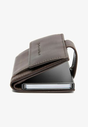 Portefeuille en cuir marron avec fermeture à rabat. Contient un carnet noir à l'intérieur avec des bords arrondis et une reliure épaisse et texturée.