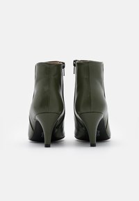 Olivgrüne Leder-Stiefeletten mit schmal zulaufendem Absatz, Reißverschluss, glatter Oberfläche und minimalistischem Design.