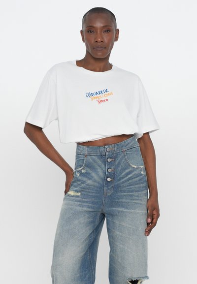 Tricou alb scurt cu text brodat în culori multiple. Blugi albastri cu talie înaltă, cu detalii uzate și închidere cu nasture în față.