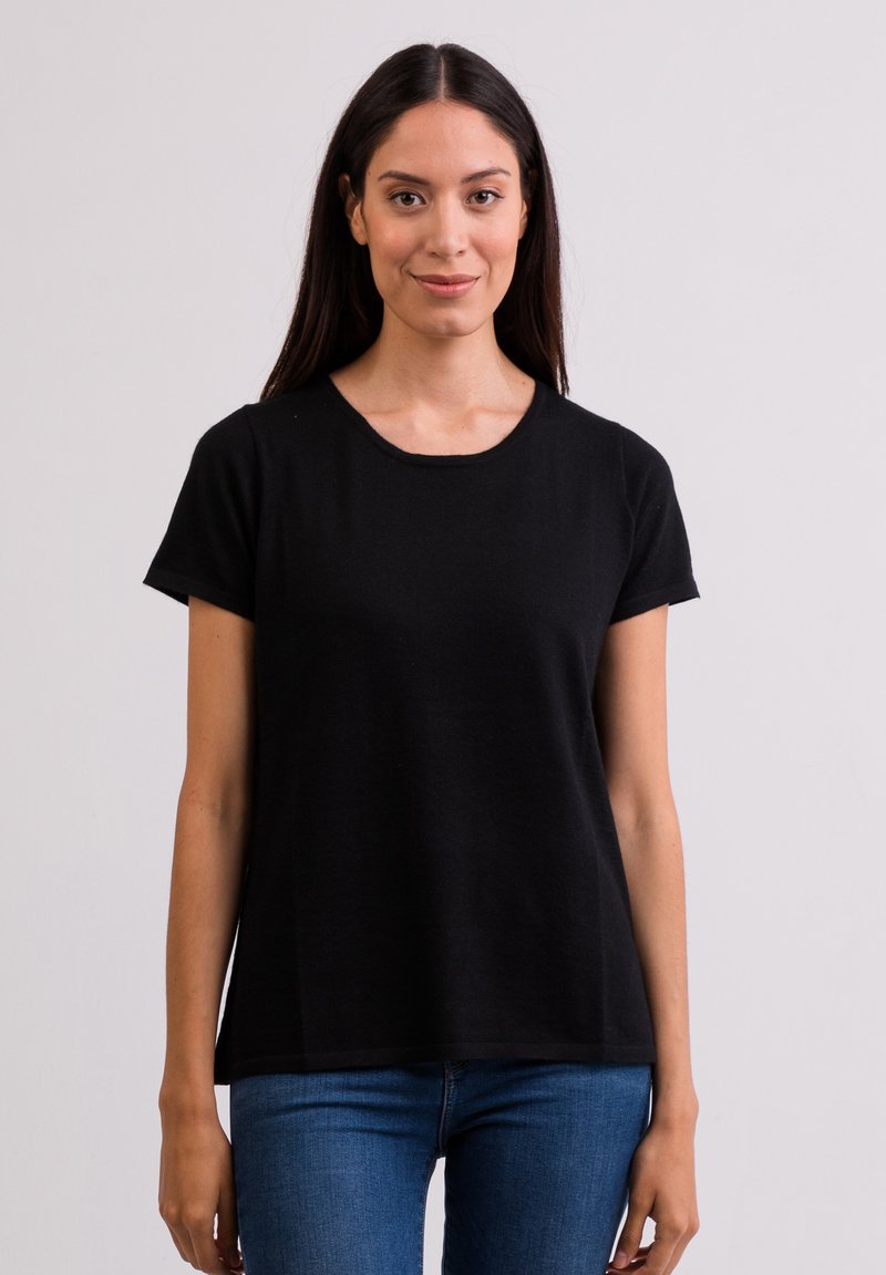 Sort kortærmet t-shirt med rund halsudskæring og afslappet pasform, lavet af blødt stof. Bæres med blå jeans, minimalistisk design, ingen synlige mønstre.