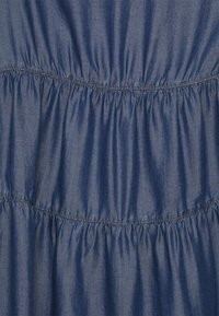 Blue denim fabric featuring gathered sections, creating a textured, structured look with elastic stitching along the seams.