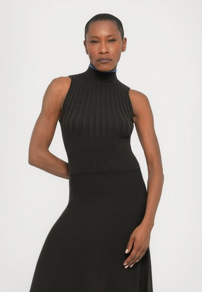 Top negru fără mâneci, cu un guler înalt cu nervuri și un model texturat, asortat cu o fustă neagră. Material neted, design ajustat.