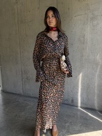 Sukienka w panterkę z długim rękawem, z wiązanym talia, swobodną sylwetką i dzwonowymi rękawami. Odcienie brązu z czerwonymi akcentami. Beżowe mule na obcasie.