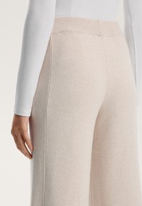 Beige vida byxor med en texturerad ribbad sidostrip, med ett mjukt stickat material och ett elastiskt midjeband.