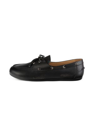 Black leather slip-on shoe with a rounded toe, decorative bow detail, and metal eyelets along the side. Smooth texture and flat sole.