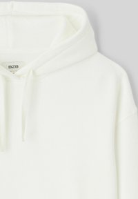 Haut à capuche blanc avec cordon de serrage, texture de tissu doux et une étiquette portant la mention "BZB" au niveau du col. Design simple et sans ornements.