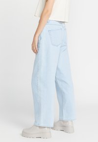 Jeans chiari a vita alta con una vestibilità rilassata. Realizzati in denim, presentano un classico design a quattro tasche e dettagli trapuntati sulle cuciture.
